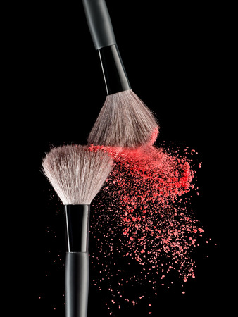 Make-up brush with pink powder explosion on black backgroundの写真素材