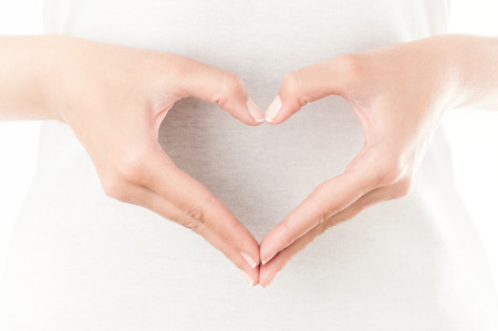 The form of heart shaped by female hands on body background isolated on white.の写真素材