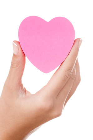 Woman hand holding a pink heart shape post-it isolated on white.の写真素材