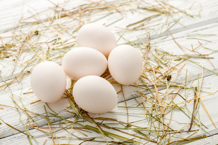 White fresh organic eggs on wooden background with straw on it. Selective focus, shallow DOF.の写真素材