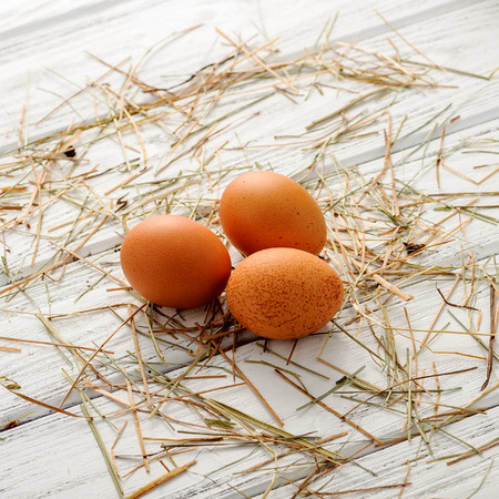 White fresh organic eggs on wooden background with straw on it. Selective focus, shallow DOF.の写真素材