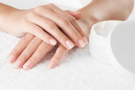 Woman's hands with cream on white towel, close-up.の写真素材