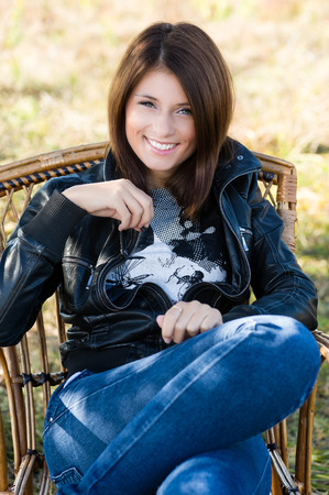 Beautiful young woman sitting on a chair outdoors. Beautiful smile on her face.の写真素材