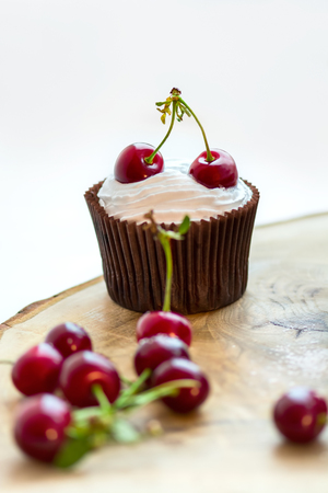 Cupcake with whipped cream and cherries on the wood, shallow DOF.\\r\\rの写真素材