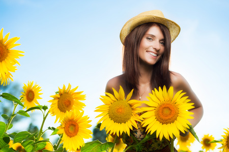 Young woman imitating her breast with two sunflowers in a fieldの写真素材