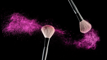 Make-up brush with pink powder explosion on black backgroundの写真素材
