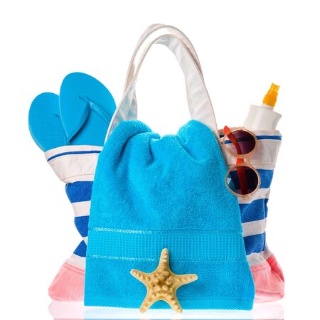 Beach bag with blue towel, flip-flops and other summer accessories isolated on white background.の写真素材