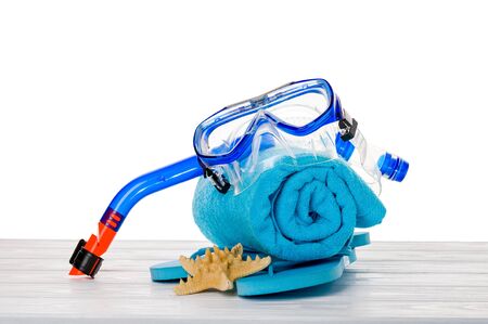 Bright beach accessories on white wooden surface isolated on white: snorkel and mask for diving, flip-flops, blue towel, starfish.の写真素材