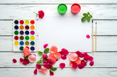 Desk of creative worker. Paints, brush, paper, rose petals and leaves. Top view background.の写真素材