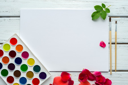 Desk of creative worker. Paints, brush, paper, rose petals and leaves. Top view background.の写真素材