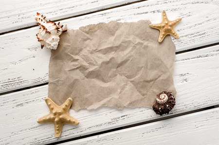 Background of creased blank paper, shells and starfishes over white wooden planks.の写真素材