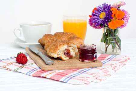A light breakfast consisting of croissants with  jam over white over wooden background.の写真素材