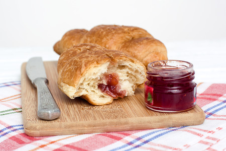 A light breakfast consisting of croissants with  jam over white over wooden background.の写真素材