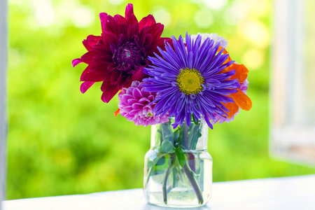 Home style fall bouquet with garden flowers on the window sill in the sunshine. Shallow DOF. Horizontal composition.の写真素材