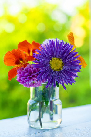 Home style fall bouquet with garden flowers on the window sill in the sunshine. Shallow DOF. Vertical composition.の写真素材