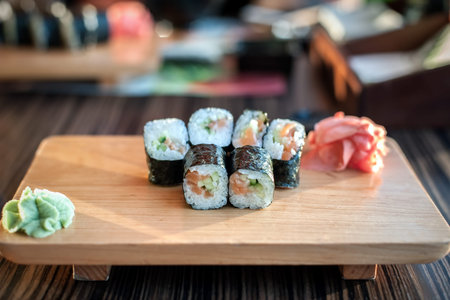 Sushi rolls served on a wooden plate in a restaurant.