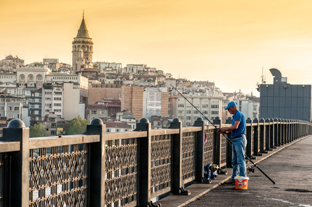 ISTANBUL, TURKEY - April 19, 2016: Fisherman on Galata Bridge with Galata tower on background on April 19, 2016 in Istanbul, Turkey. Galata Bridge is one of the famous entertainment place in Istanbul.のeditorial素材