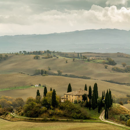 Lonely farmhouse with golden meadow hills. Tuscan autumn landscape. Tuscan Villa on countryside, San Quirico d´Orcia, Tuscany, Italy. Square composition.の写真素材