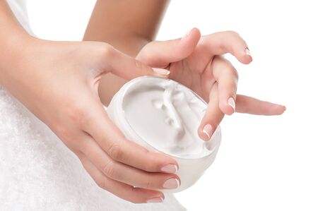 Woman applying body cream. Close-up composition of hands with white jar isolated on white background. Horizontal composition.の写真素材