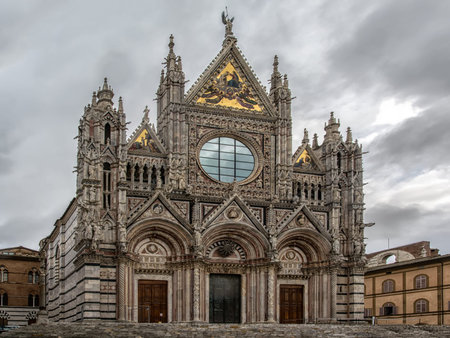 Siena cathedral under a grey cloudy sky, dedicated to Santa Maria Assunta, in the city of Siena, Italy.の写真素材