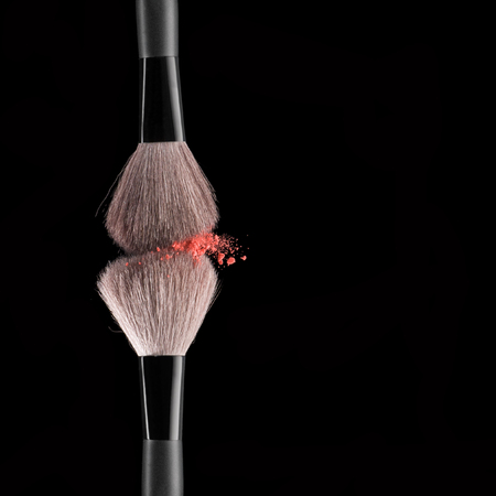 Make-up brushes with pink powder explosion on black backgroundの写真素材