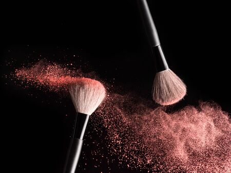 Make-up brushes with pink powder explosion on black backgroundの写真素材