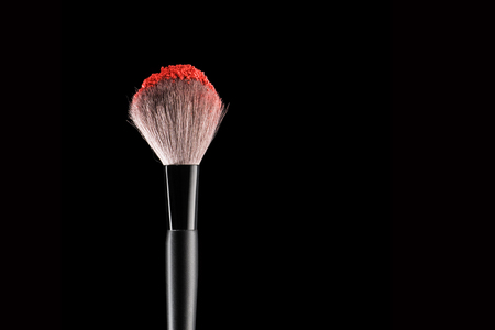 Make-up brush with red blush on black, close-up.の写真素材