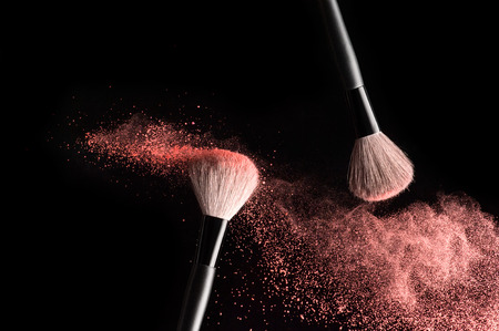 Make-up brushes with pink powder explosion on black backgroundの写真素材