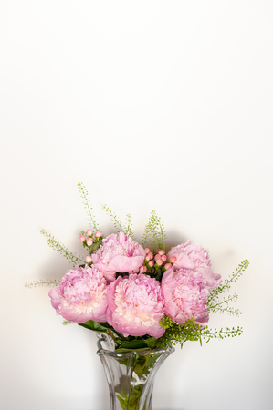 Bunch of pink peonies in glass vase on white background.の写真素材