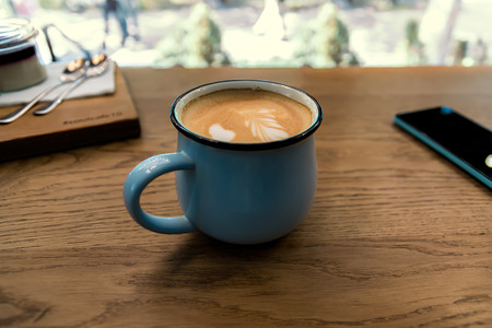 Ð¡appuccino or coffee in blue cup, smartphone and panna cotta on wooden table background. Concept photo, shallow DOF.の写真素材