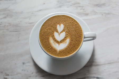 A Cup of hot cappuccino art coffee on white table, leaf coffee art, top viewの写真素材