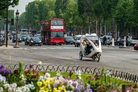 PARIS, FRANCE - APRIL 29, 2011: The Avenue des Champs-Elysees with car traffic and sightseeing red bus in springtime, Paris, France. It is known for its theatres, cafés, and luxury shops.のeditorial素材