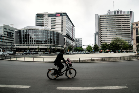 PARIS, FRANCE - APRIL 28, 2011: blurred with a motion biker silhouette on the Place de Catalogne, Paris, France. Hotel Concorde Montparnasse on the background.のeditorial素材