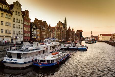 Gdansk, Poland - May 19, 2018: Colored houses on the promenade of the river at dawn with moored...