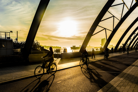 Silhouettes of unrecognizable bicyclists cycling at sunset in Amsterdam railway station.の写真素材