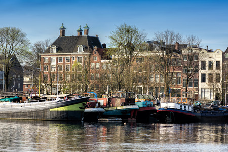 AMSTERDAM, NETHERLANDS - APRIL 10, 2018: Amsterdam cityscape with typical dutch houses and boats from the Oosterdok in the Netherlands.のeditorial素材