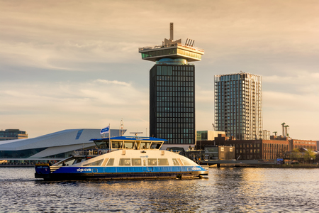 AMSTERDAM, NETHERLANDS - APRIL 13, 2018: The Aâdam Tower at dawn - a high building in Amsterdam with swing standing, with city ferry on foreground.のeditorial素材