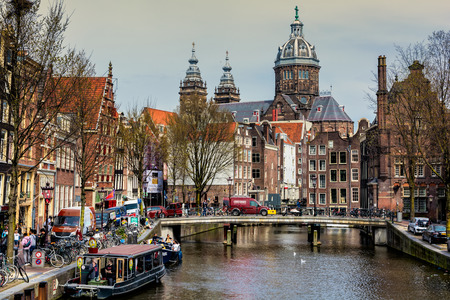 AMSTERDAM, NETHERLANDS - APRIL 10, 2018: St. Nicholas Church and Amsterdam canal with typical dutch houses.のeditorial素材