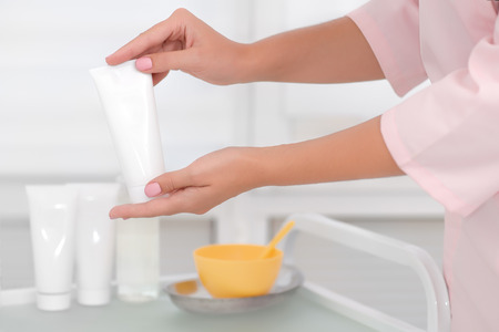 Hand skin care. Female hands holding cream tube, beautiful beautician woman hands with close-up over natural white background. Nails Beauty And Body Care Concept. Shallow DOF.の写真素材