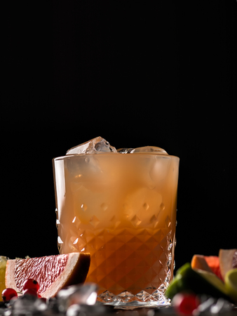 Glass of orange juice and ice with fruits slices (orange, grapefruit, lime and red currant) over black background. Close-up, shallow DOF, soft focus, with copy space.の写真素材