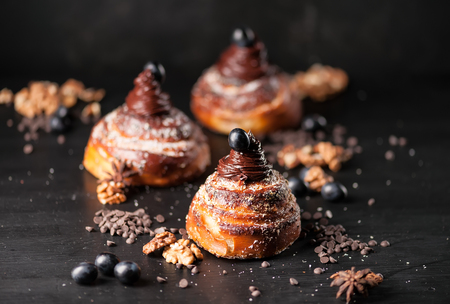 Sweet buns with chocolate cream, spices and berries on the dark background. Selective focus, shallow DOF. Photo taken on workshop.の写真素材