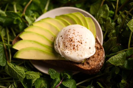 Healthy sandwich with avocado and poached egg on the mint leaves background. Breakfast food concept....