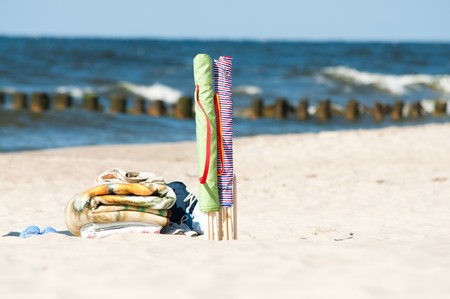 colorful textile beach windbreak stuck in sand and towelsの写真素材