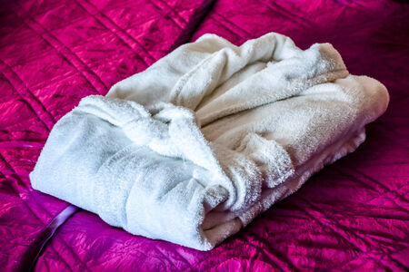 white bathrobe on the bed in hotel roomの写真素材