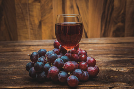 glass of wine or grape juice and fruit on wooden table