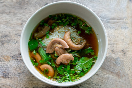 Rice vermicelli soup with mushrooms in bowl on wooden table