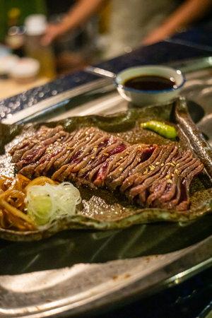 Thin slices of raw beef on a beef grill, meat starting to sear and sizzle, authentic Japanese...