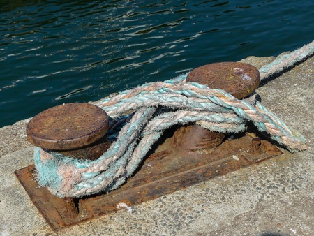 Rusty bollard with mooring rope secured at the pierの写真素材