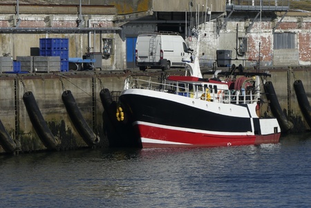 Black and red fishing boat Alongside the wharf at the fishing harbor of Lorient, Brittany France.の写真素材