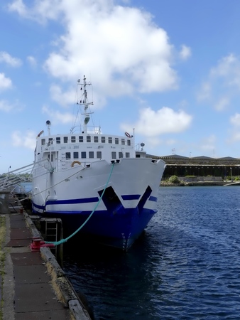 Ferry boat docked at Keroman Harbor, Lorient, France with warehouse and cloudy sky in the backgroundのeditorial素材